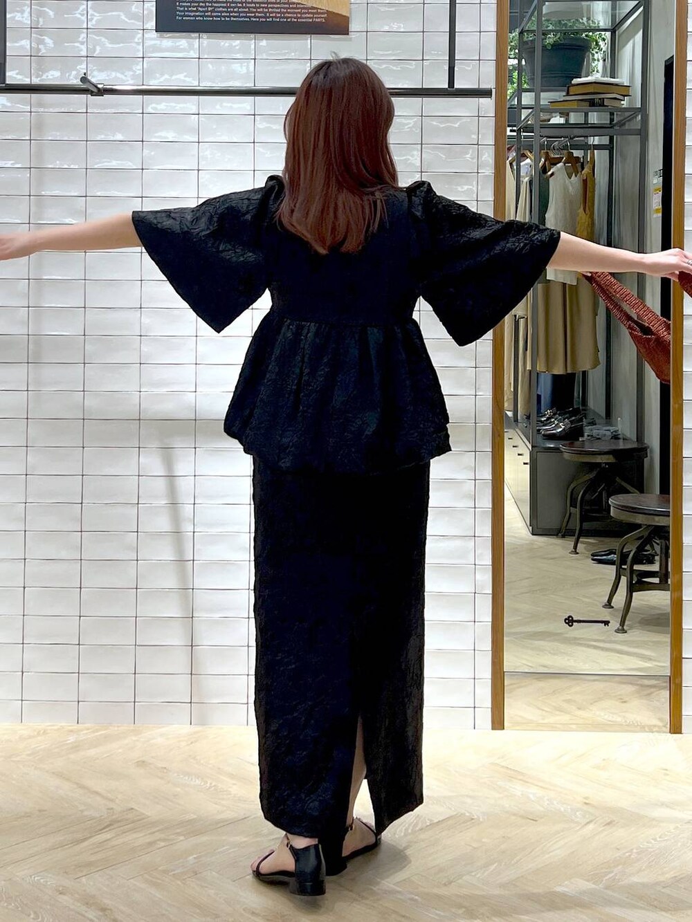 ブラウン系のハンドバッグ、ブラック系のサンダル、ブラック系のワンピースを着用したレディースの夏コーディネートの6枚目の写真