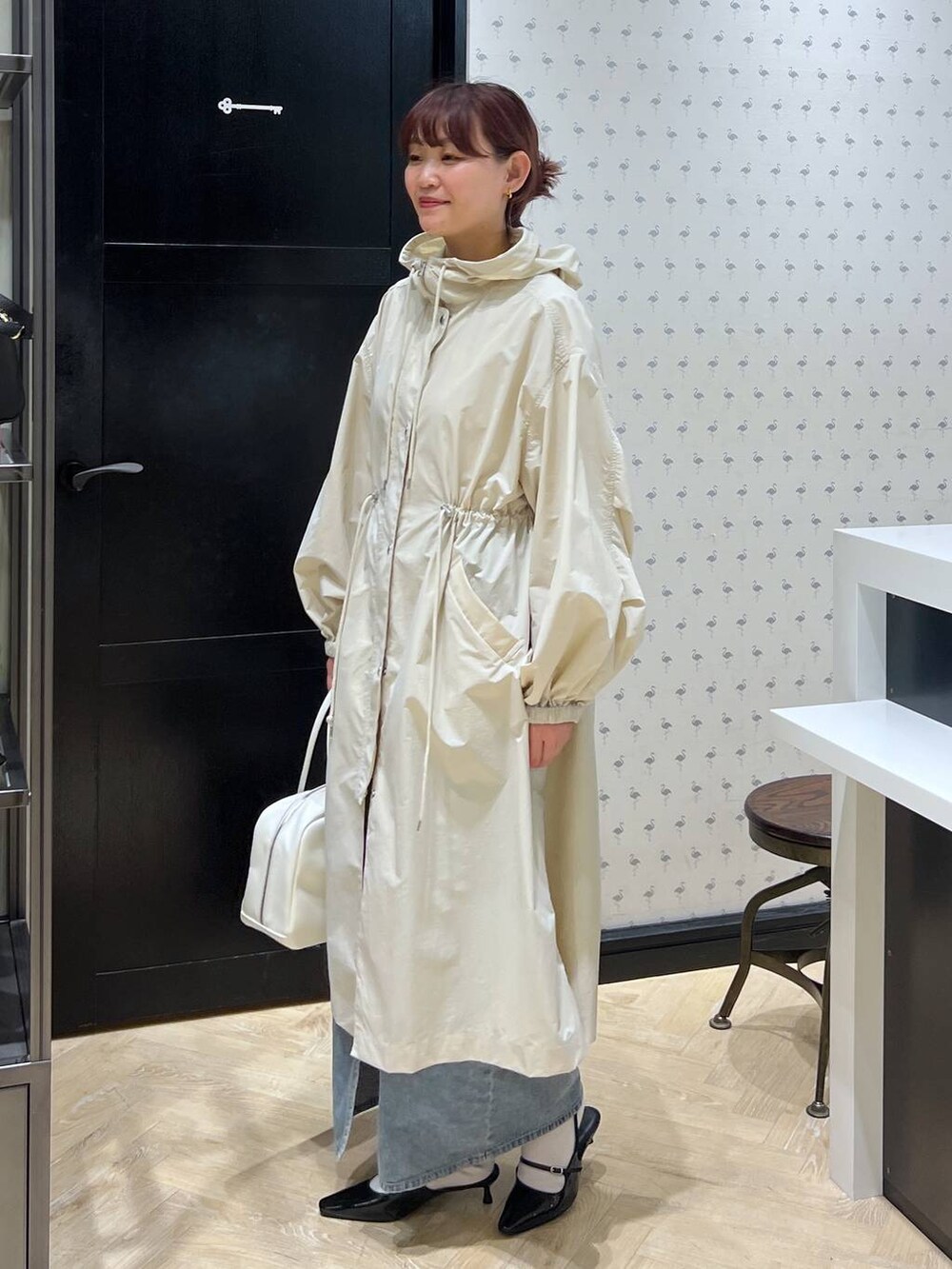 ブルー系のデニムスカート、ホワイト系のボストンバッグ、ブラック系のパンプスを着用したレディースの春コーディネートの2枚目の写真