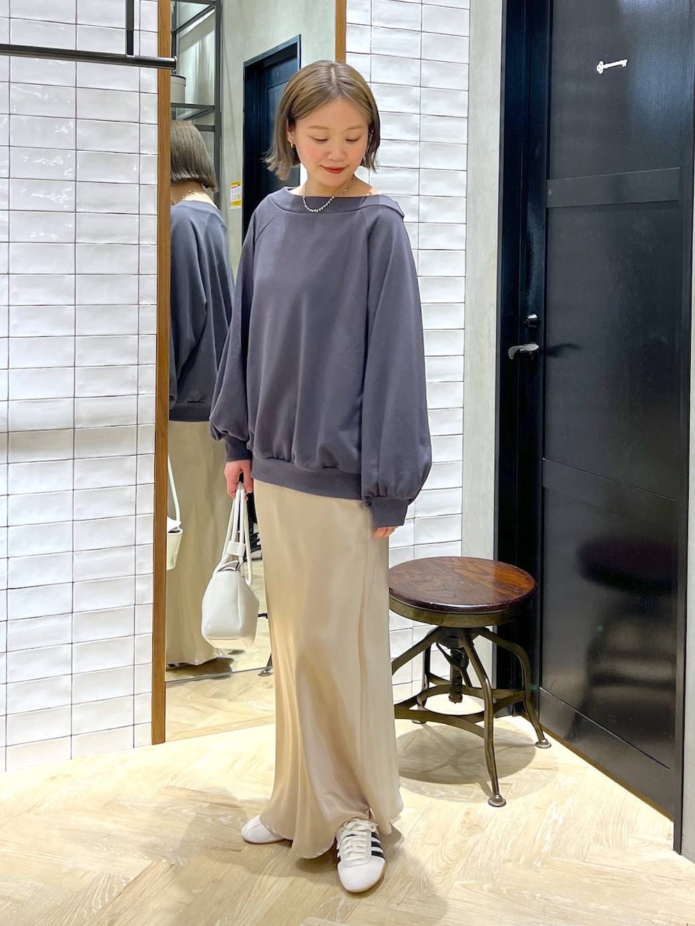 ベージュ系のスカート、ホワイト系のスニーカー、ホワイト系のショルダーバッグを着用したレディースの冬コーディネートの6枚目の写真