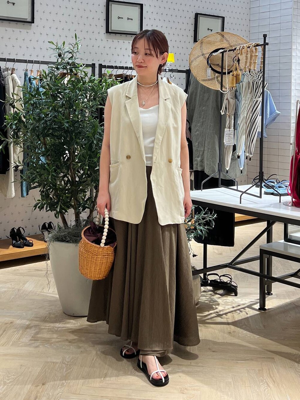 ブラウン系のかごバッグ、ホワイト系のキャミソール、ベージュ系のベストを着用したレディースの夏コーディネートの2枚目の写真
