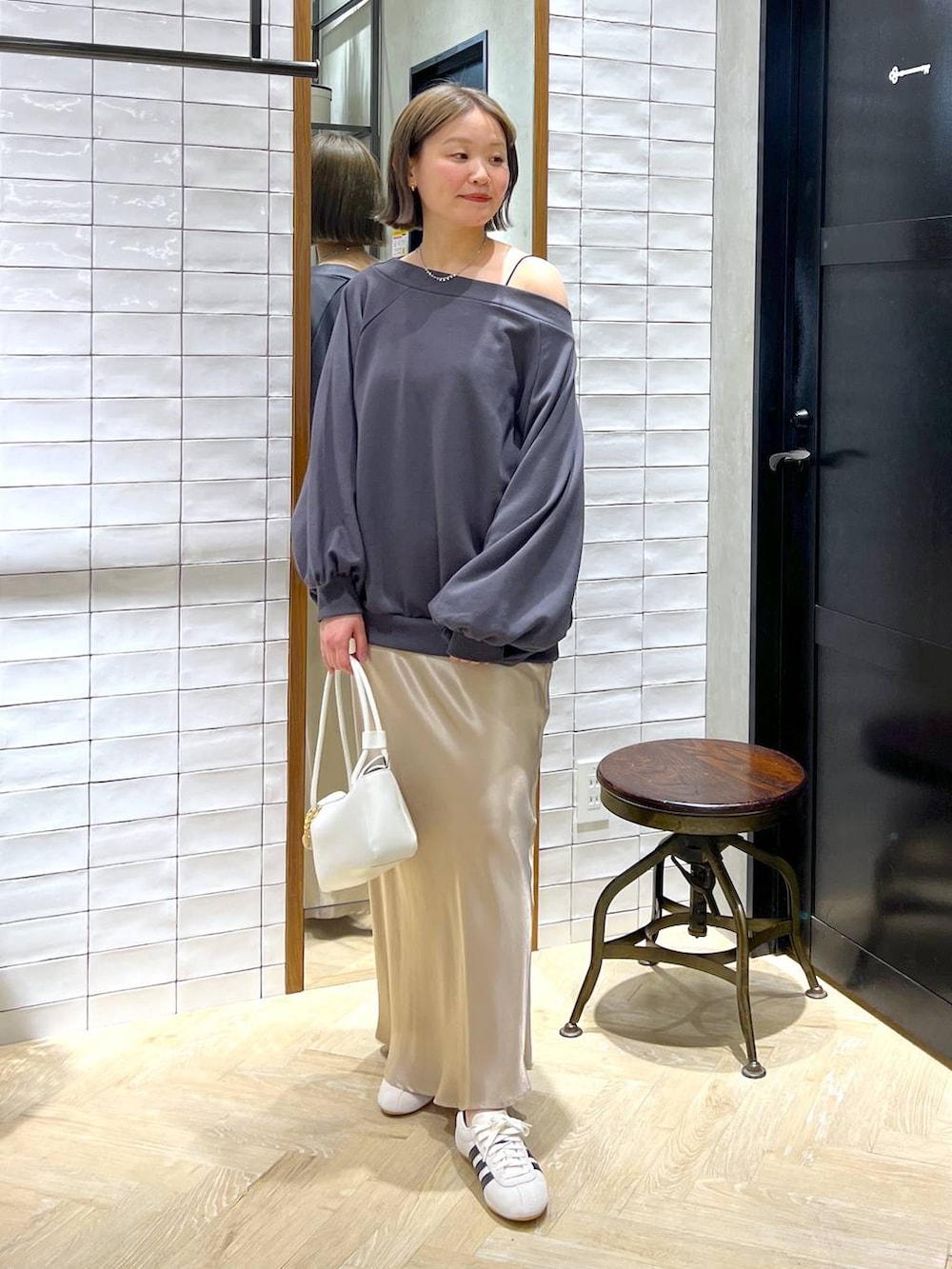 ベージュ系のスカート、ホワイト系のスニーカー、ホワイト系のショルダーバッグを着用したレディースの冬コーディネートの2枚目の写真