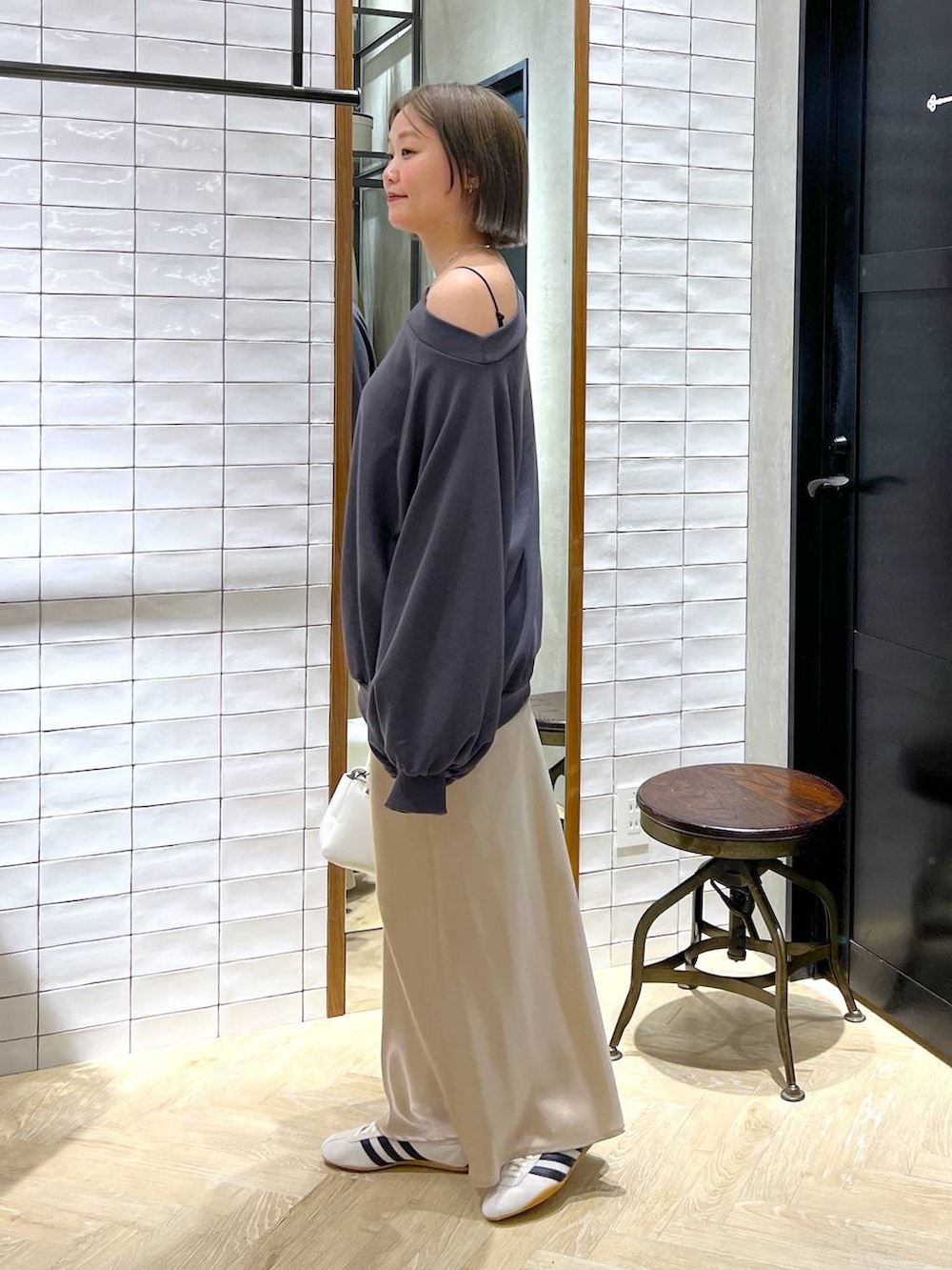 ベージュ系のスカート、ホワイト系のスニーカー、ホワイト系のショルダーバッグを着用したレディースの冬コーディネートの3枚目の写真