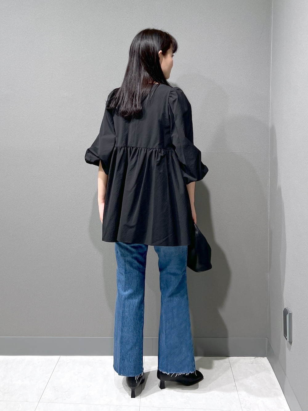 ブラック系のシャツ/ブラウス、ブルー系のデニムパンツ、ブラック系のハンドバッグを着用したレディースの秋コーディネートの3枚目の写真