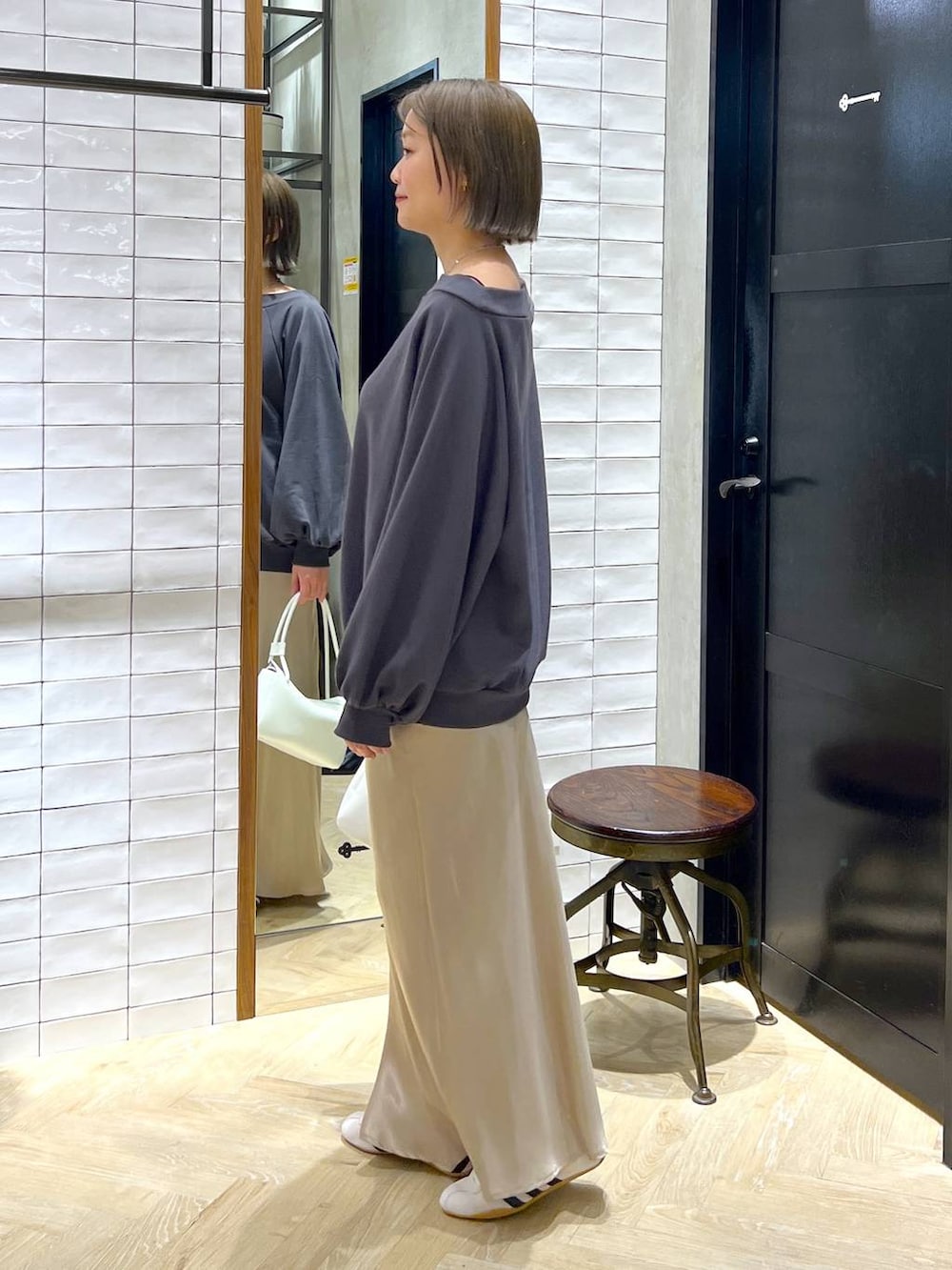 ベージュ系のスカート、ホワイト系のスニーカー、ホワイト系のショルダーバッグを着用したレディースの冬コーディネートの7枚目の写真