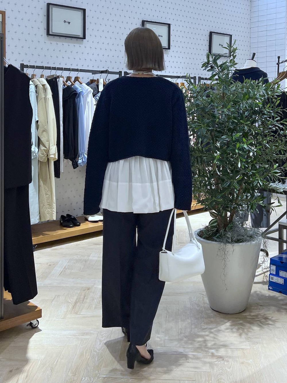 ブルー系のスラックス、ブルー系のカーディガン/ボレロ、ホワイト系のショルダーバッグを着用したレディースの冬コーディネートの5枚目の写真