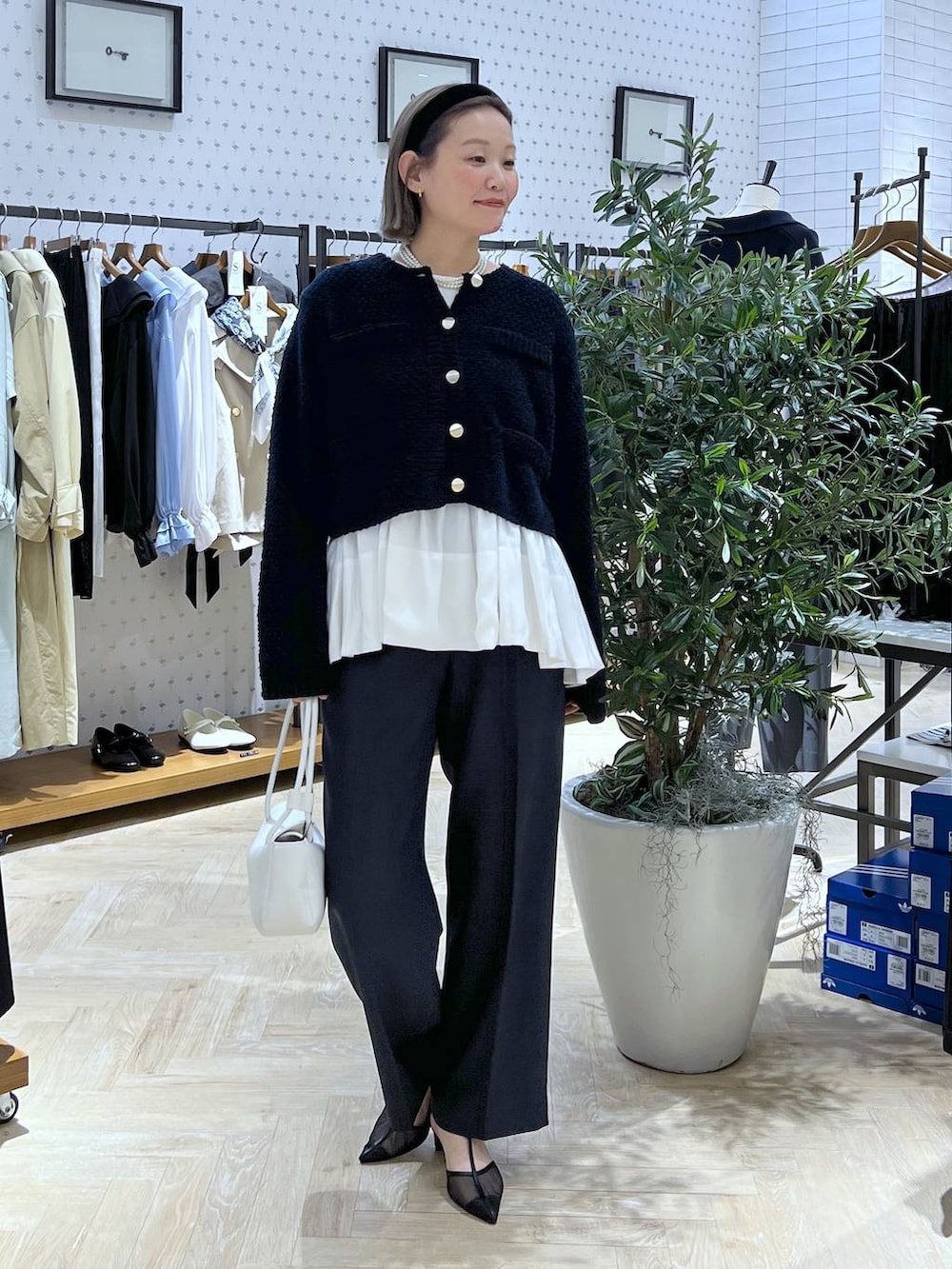 ブルー系のスラックス、ブルー系のカーディガン/ボレロ、ホワイト系のショルダーバッグを着用したレディースの冬コーディネートの2枚目の写真