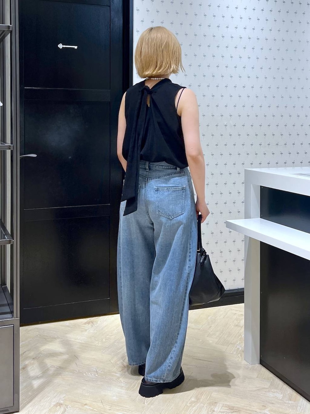 ブラック系のスリッポン、ブルー系のデニムパンツ、ブラック系のショルダーバッグを着用したレディースの夏コーディネートの5枚目の写真