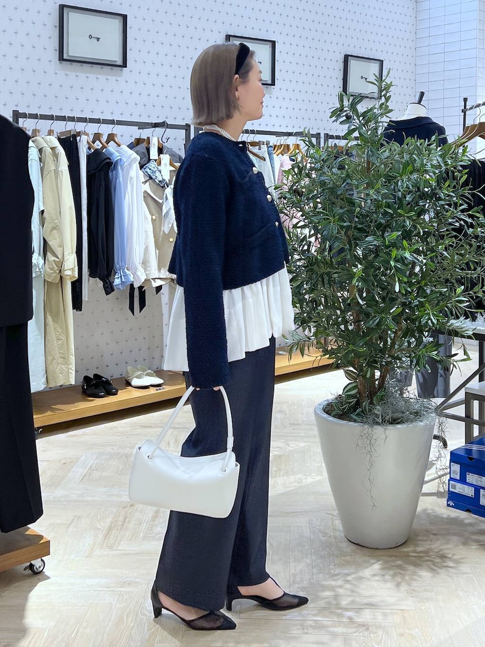 ブルー系のスラックス、ブルー系のカーディガン/ボレロ、ホワイト系のショルダーバッグを着用したレディースの冬コーディネートの4枚目の写真