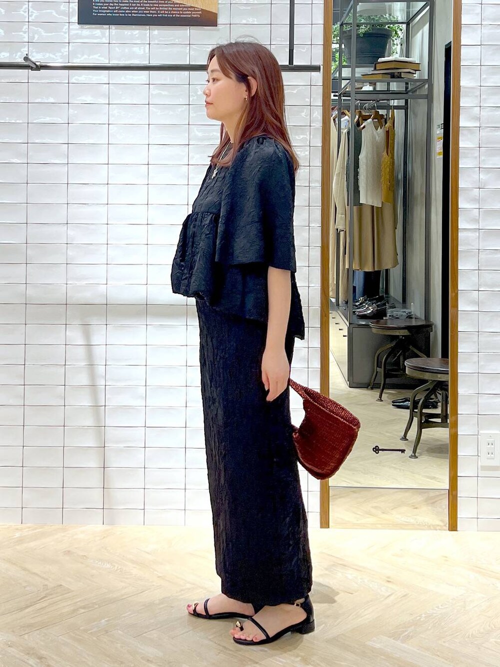 ブラウン系のハンドバッグ、ブラック系のサンダル、ブラック系のワンピースを着用したレディースの夏コーディネートの3枚目の写真