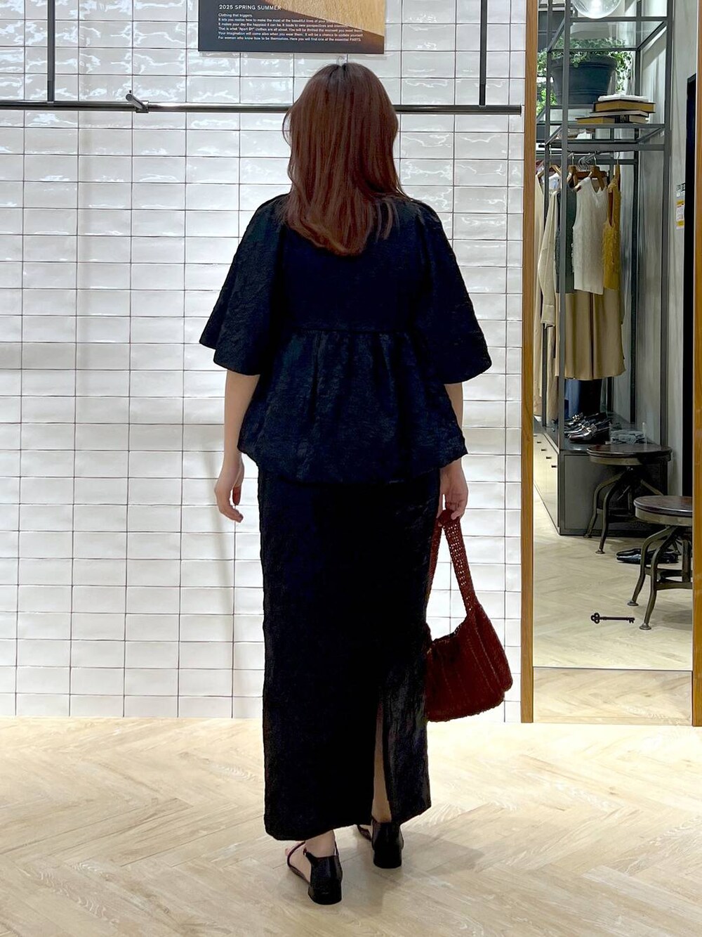 ブラウン系のハンドバッグ、ブラック系のサンダル、ブラック系のワンピースを着用したレディースの夏コーディネートの4枚目の写真