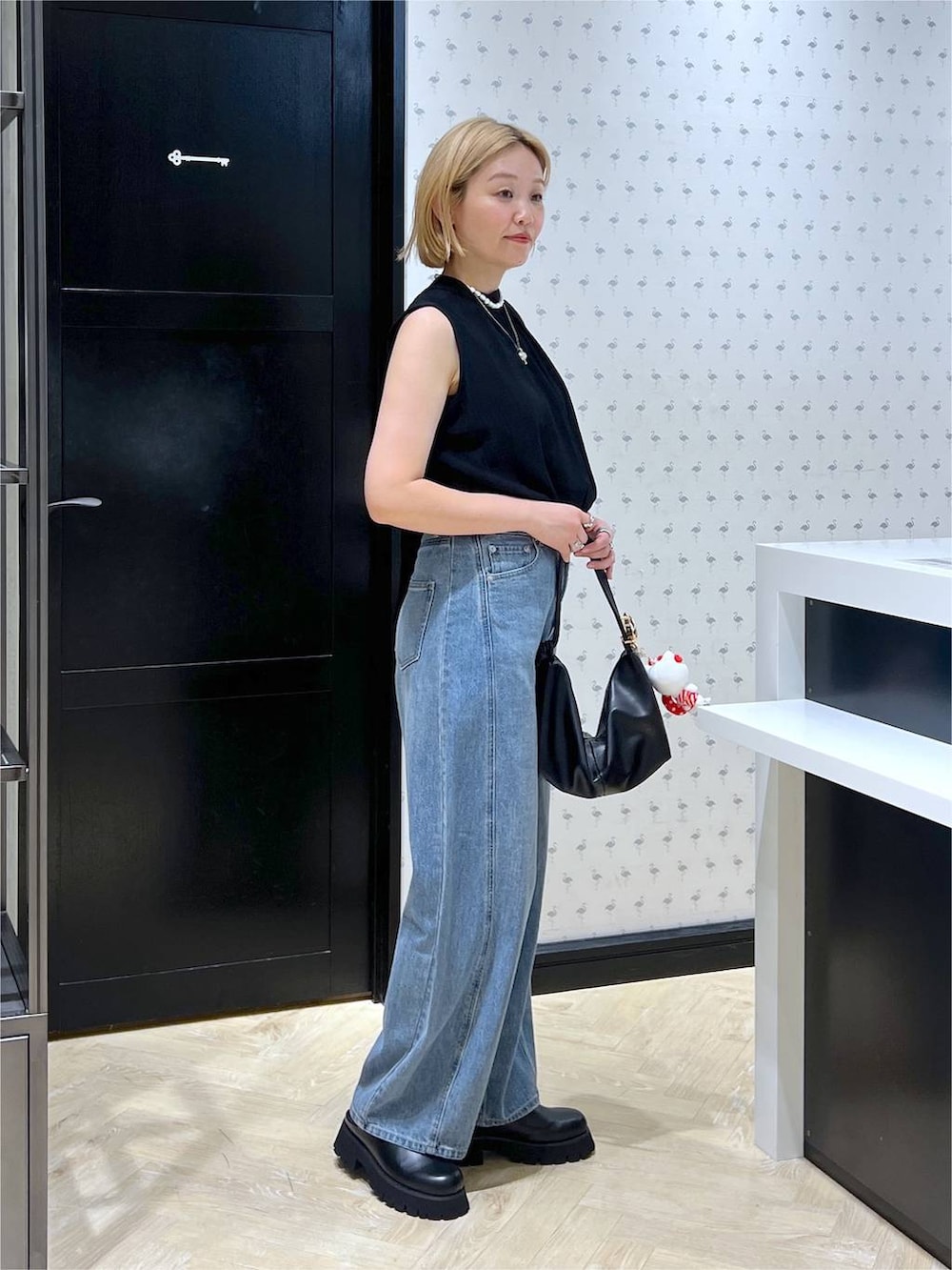 ブラック系のスリッポン、ブルー系のデニムパンツ、ブラック系のショルダーバッグを着用したレディースの夏コーディネートの4枚目の写真