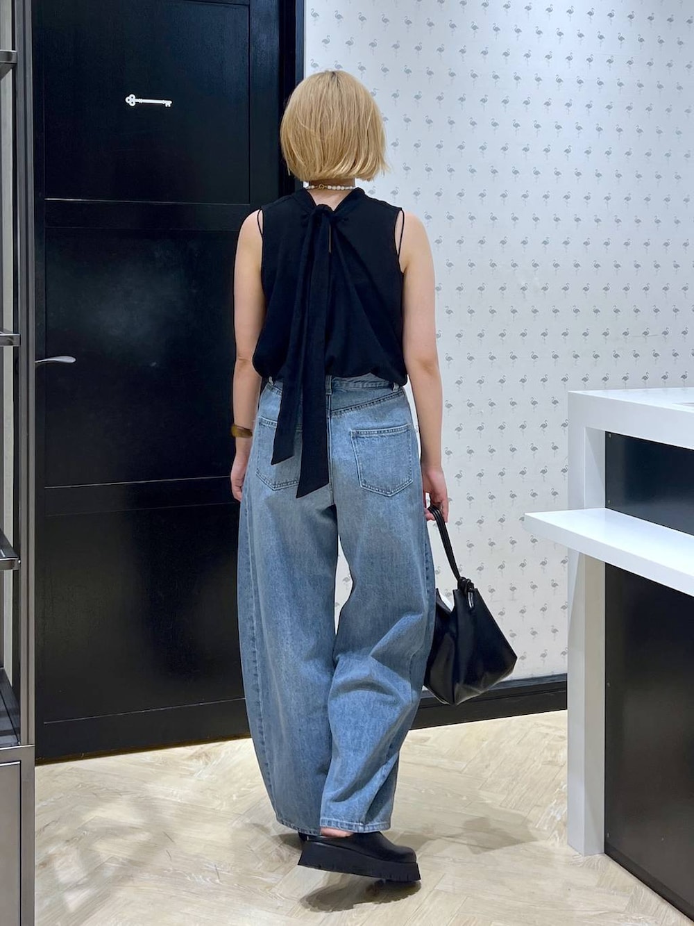 ブラック系のスリッポン、ブルー系のデニムパンツ、ブラック系のショルダーバッグを着用したレディースの夏コーディネートの6枚目の写真