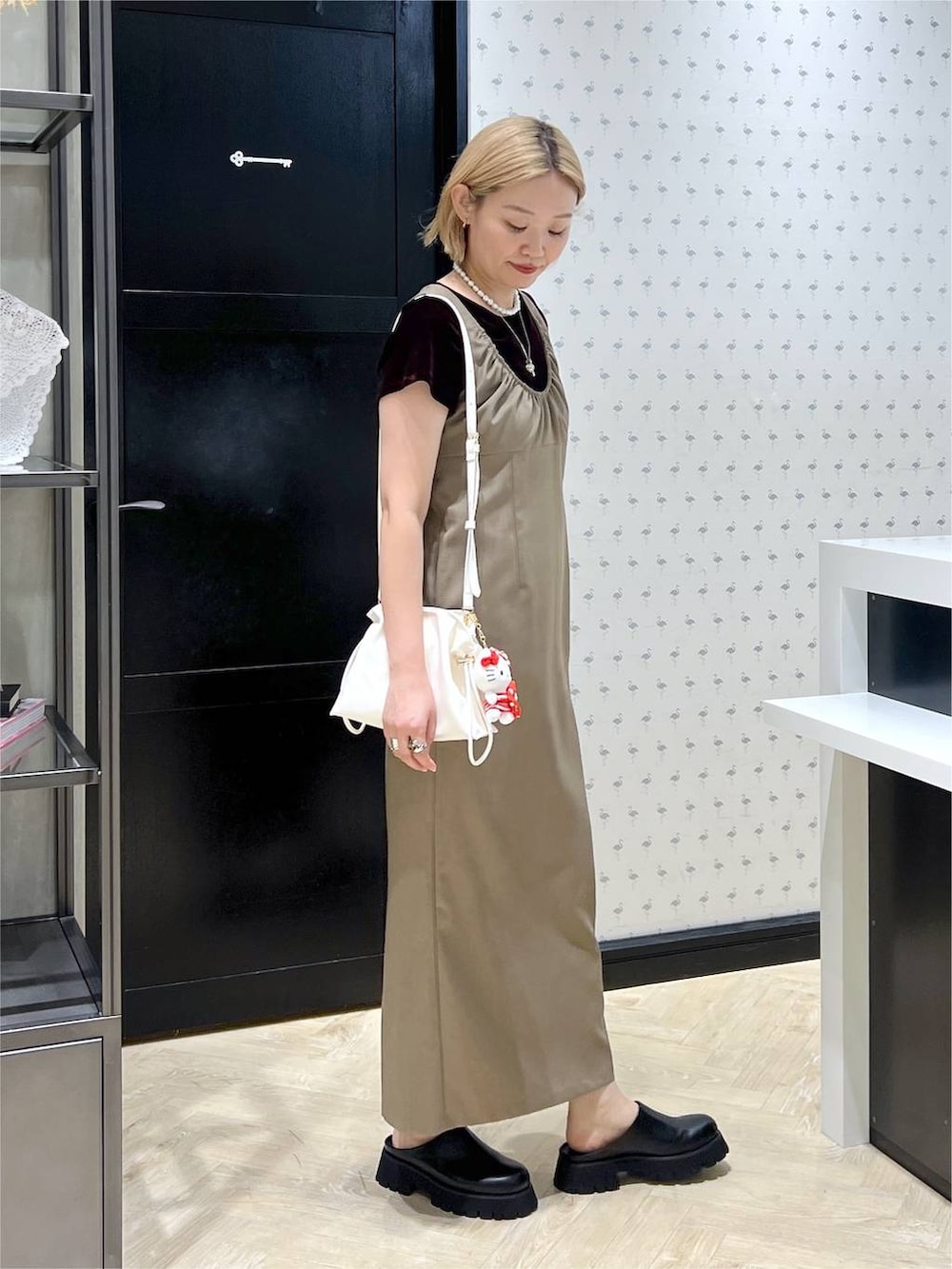 ホワイト系のショルダーバッグ、ブラック系のスリッポン、ベージュ系のワンピースを着用したレディースの夏コーディネートの3枚目の写真