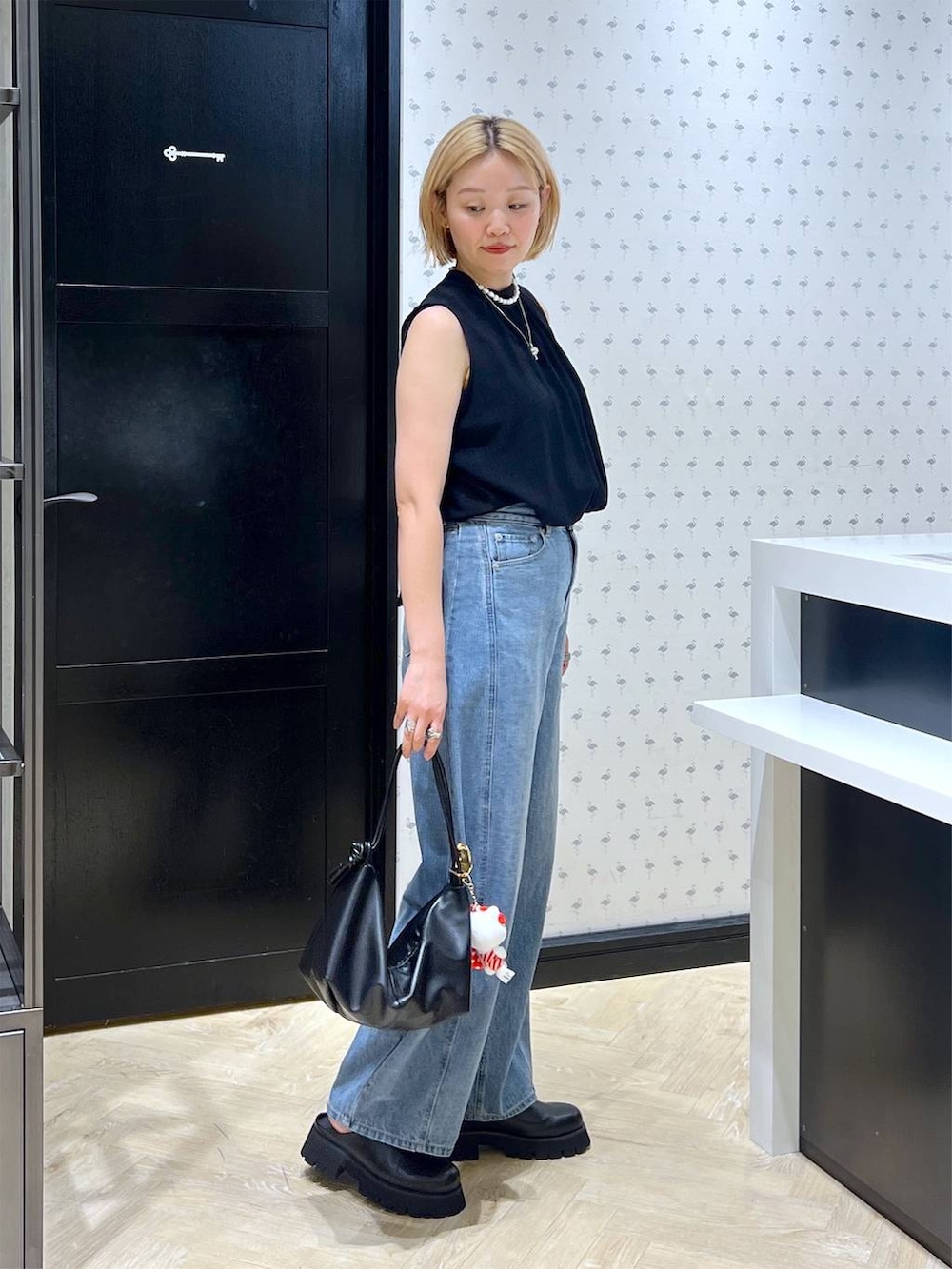 ブラック系のスリッポン、ブルー系のデニムパンツ、ブラック系のショルダーバッグを着用したレディースの夏コーディネートの3枚目の写真