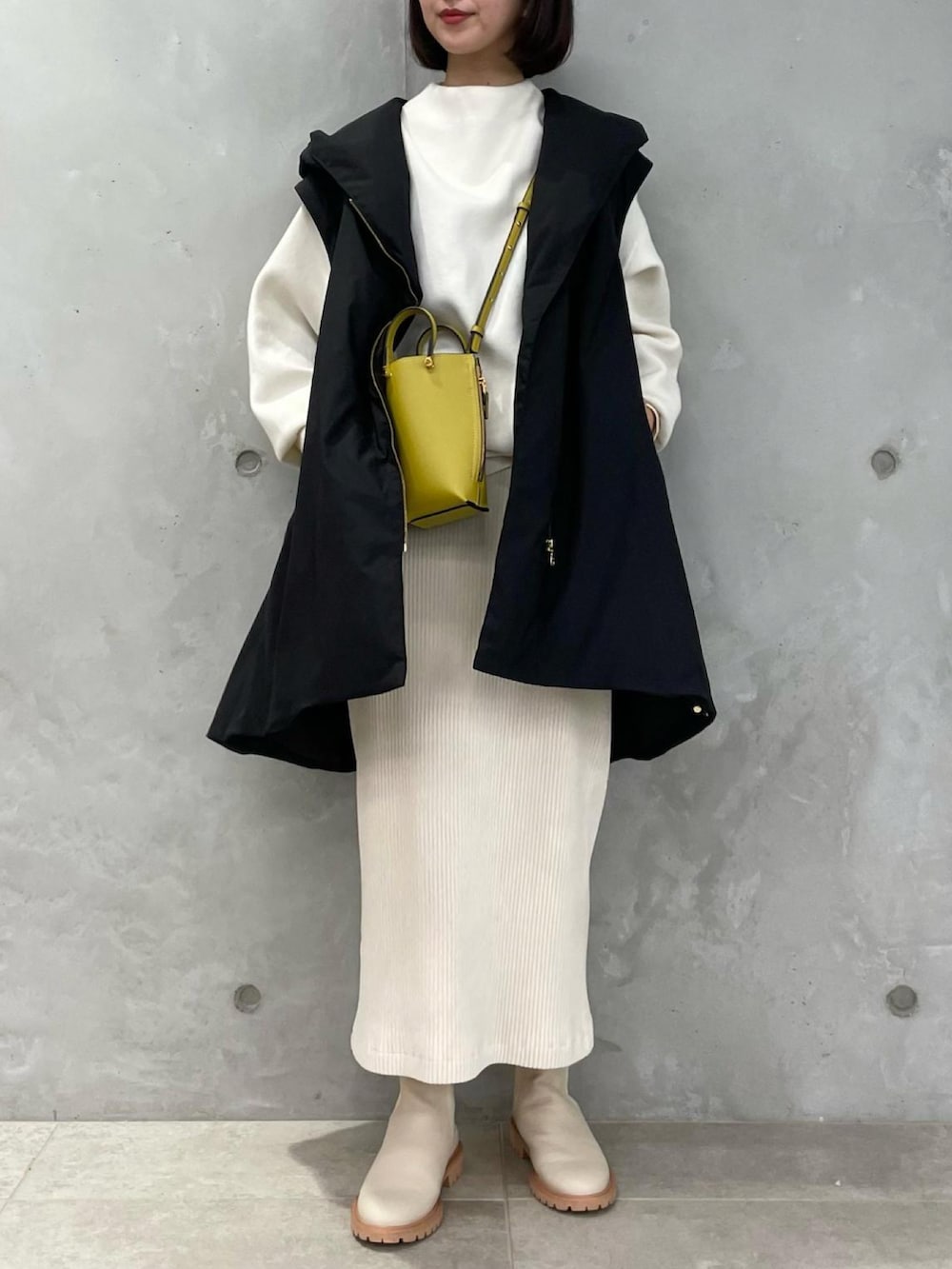 ブラック系のダウンジャケット/コート、ホワイト系のスカート、ホワイト系のブーツを着用したレディースの秋コーディネートの2枚目の写真