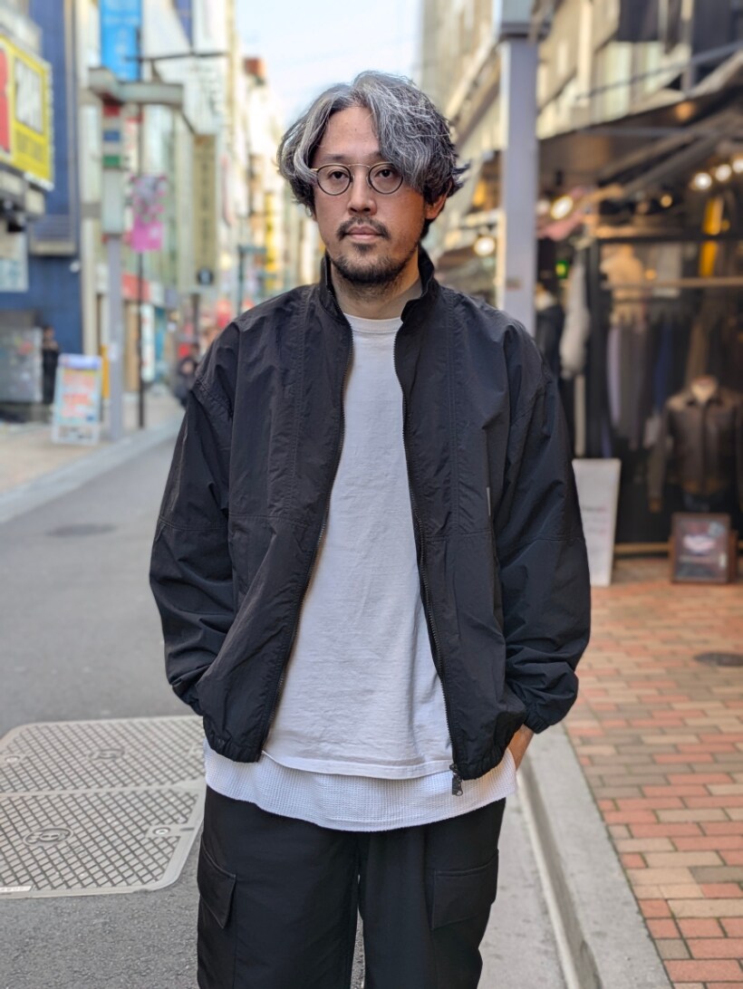 ブラック系のナイロンジャケット、ブラック系のスニーカー、ブラック系のカーゴパンツを着用したメンズの春コーディネートの2枚目の写真