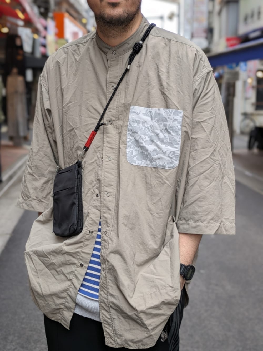 グレー系のシャツ/ブラウス、ブラック系のショルダーバッグ、ブラック系のスマホグッズを着用したメンズの夏コーディネートの2枚目の写真