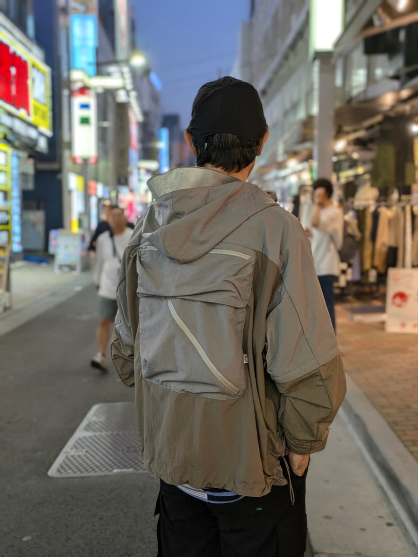 ブルー系のTシャツ/カットソー、ベージュ系のマウンテンパーカー、ブラック系のキャップを着用したメンズの秋コーディネートの4枚目の写真
