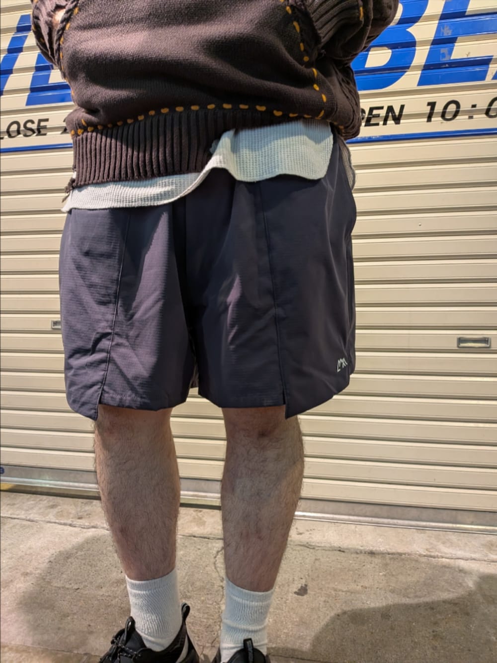 ブラウン系のニット/セーター、グレー系のその他パンツ、ブラック系のサンダルを着用したメンズの夏コーディネートの4枚目の写真
