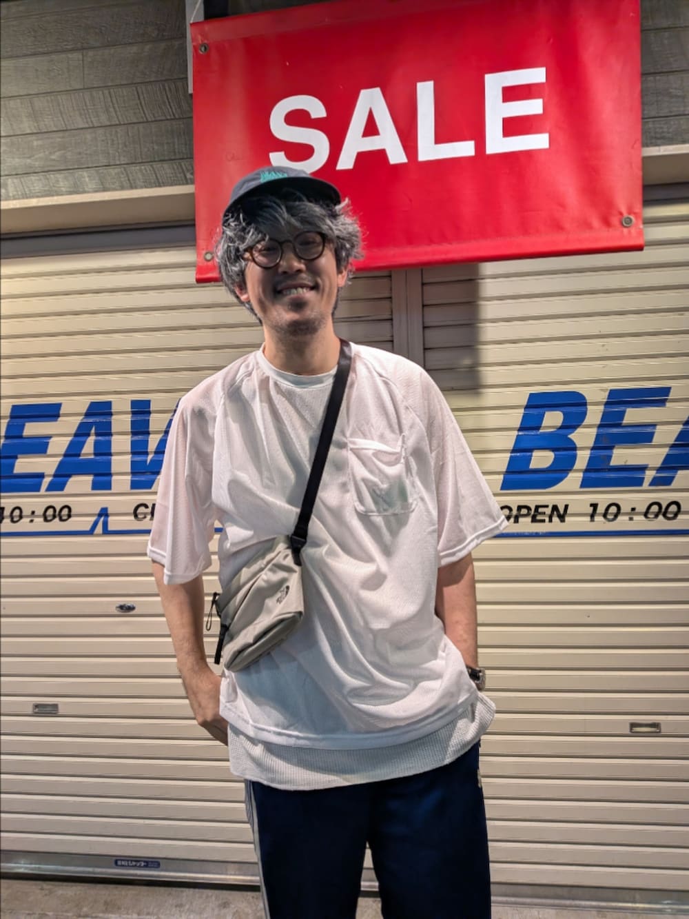 グレー系のショルダーバッグ、ホワイト系のTシャツ/カットソー、ブラック系のサンダルを着用したメンズの夏コーディネートの2枚目の写真