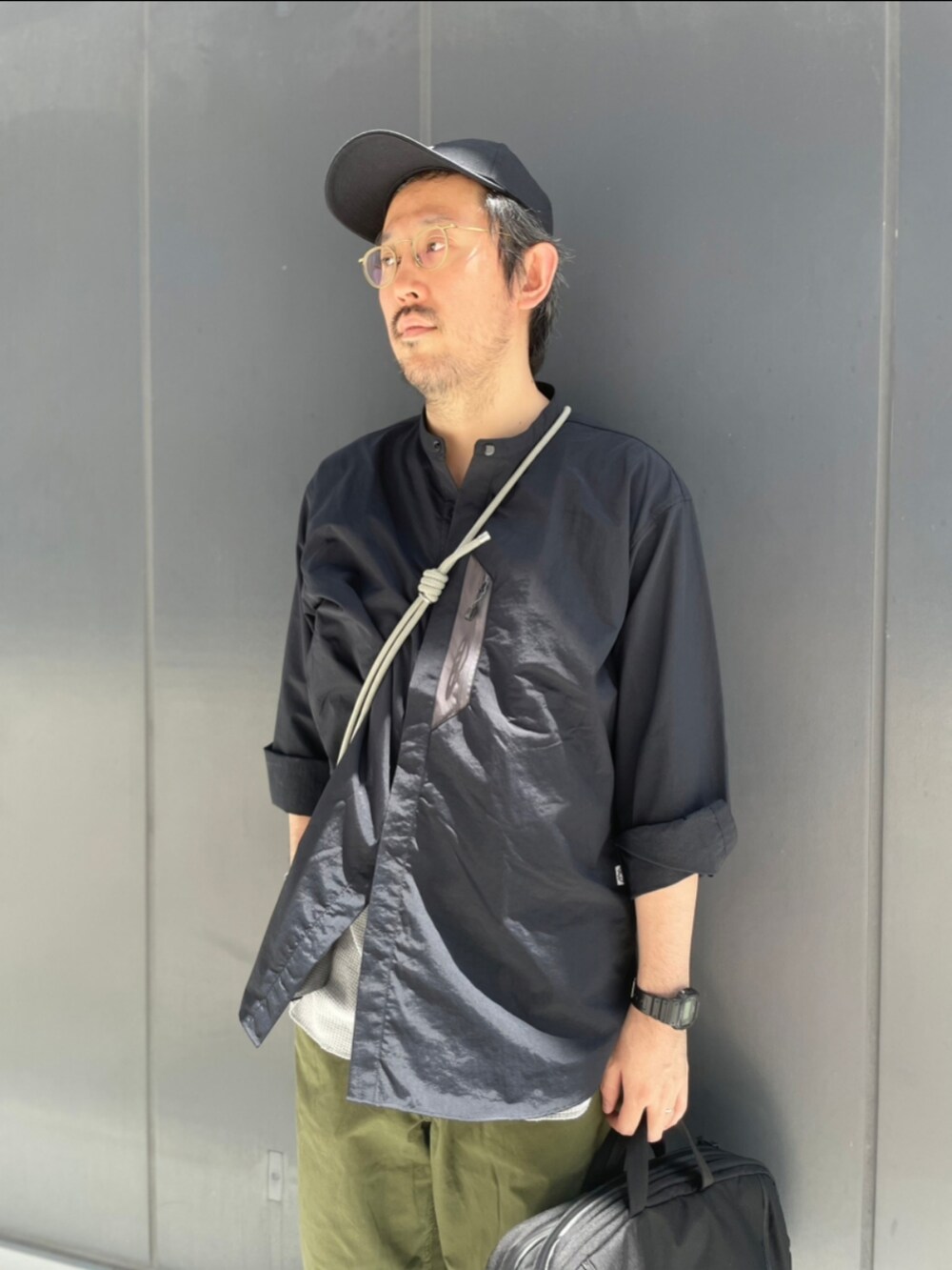 グリーン系のその他パンツ、ブラック系のシャツ/ブラウス、グリーン系のスマホグッズを着用したメンズの夏コーディネートの2枚目の写真