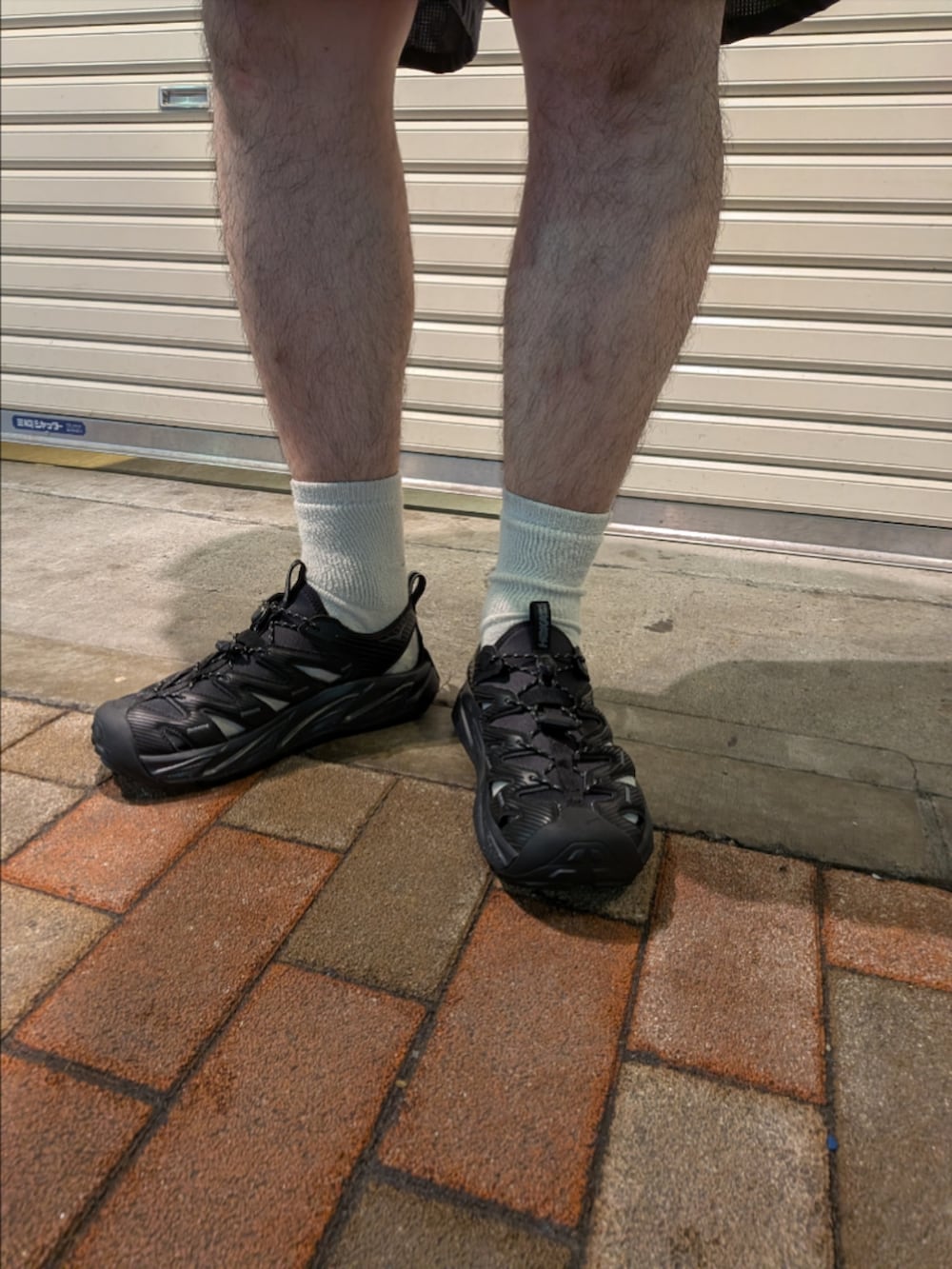 ブラウン系のニット/セーター、グレー系のその他パンツ、ブラック系のサンダルを着用したメンズの夏コーディネートの3枚目の写真