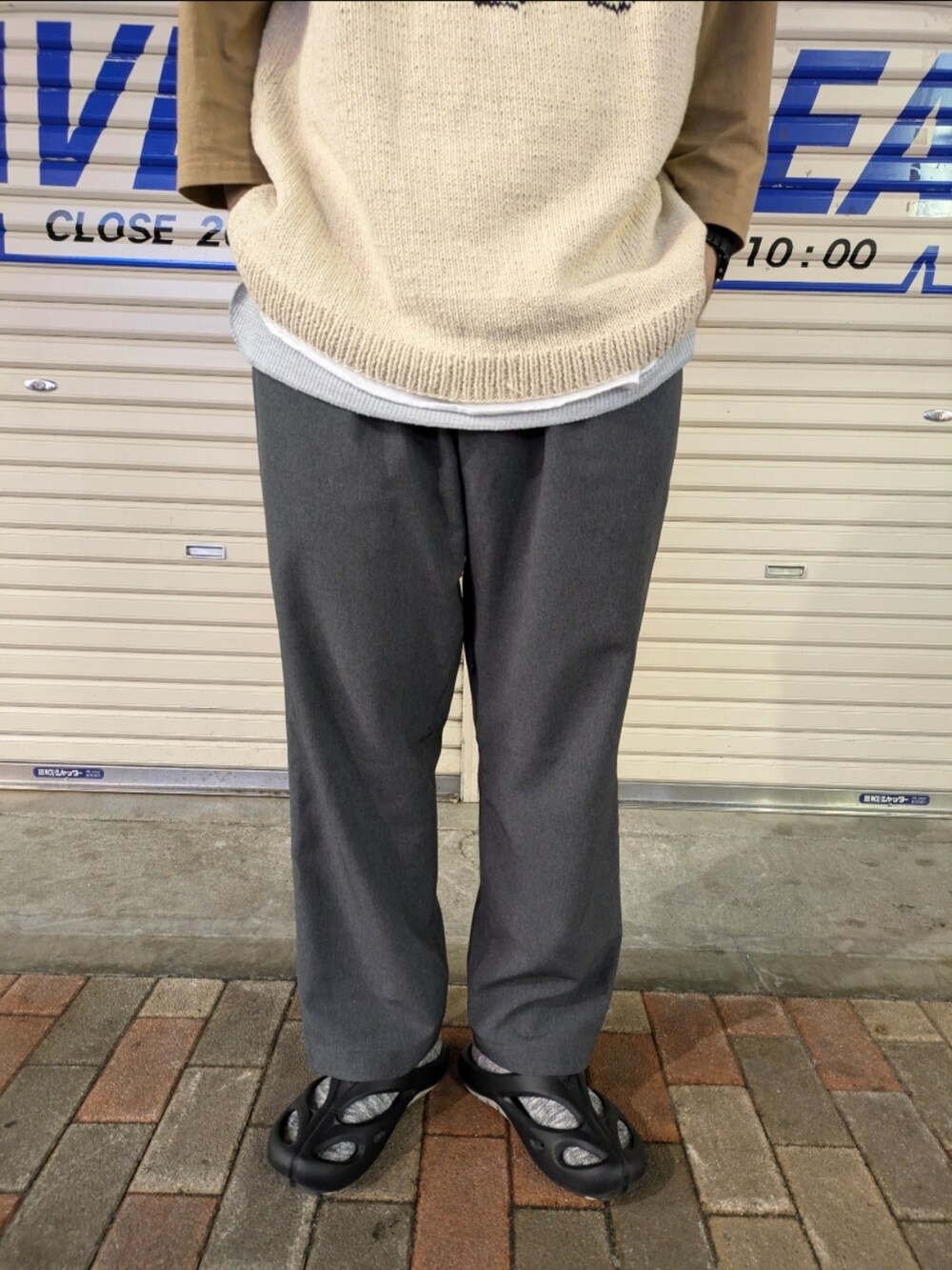 ブルー系のスラックス、ブラウン系のTシャツ/カットソー、ゴールド系のニット/セーターを着用したメンズの夏コーディネートの3枚目の写真