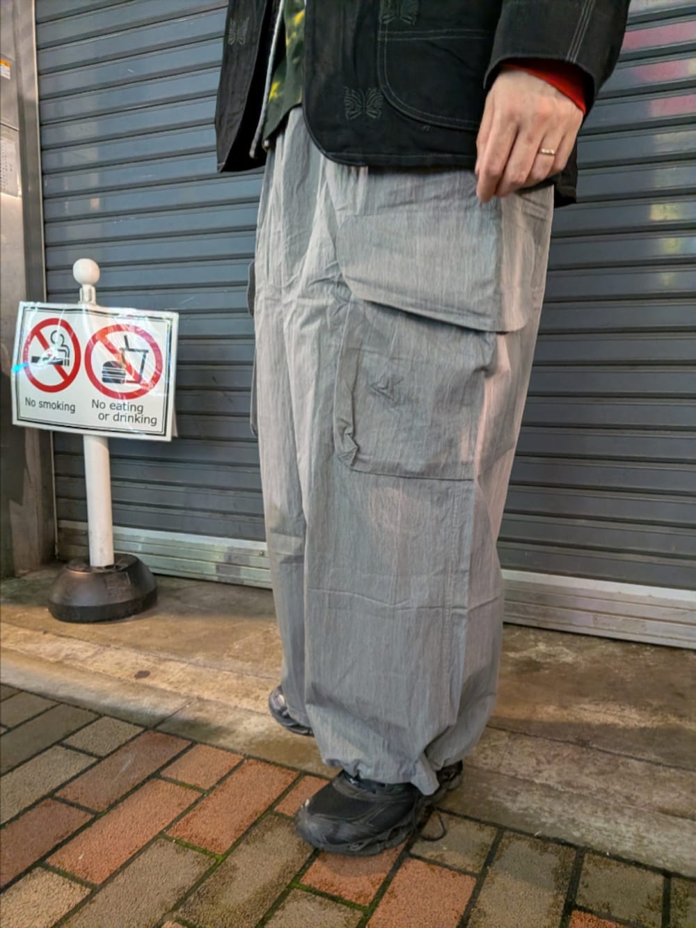 ブラック系のナイロンジャケット、グレー系のカーゴパンツ、ホワイト系のトートバッグを着用したメンズの春コーディネートの4枚目の写真