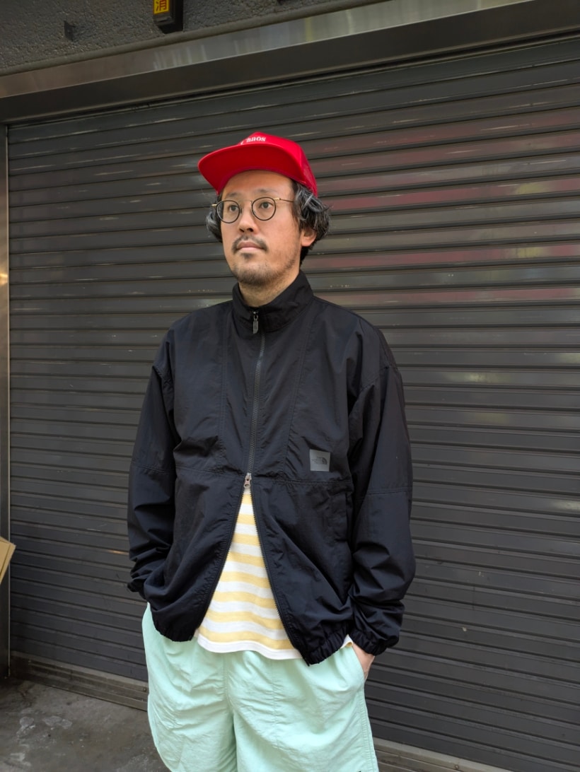 ブラック系のナイロンジャケット、グレー系のスニーカーを着用したメンズの春コーディネートの2枚目の写真