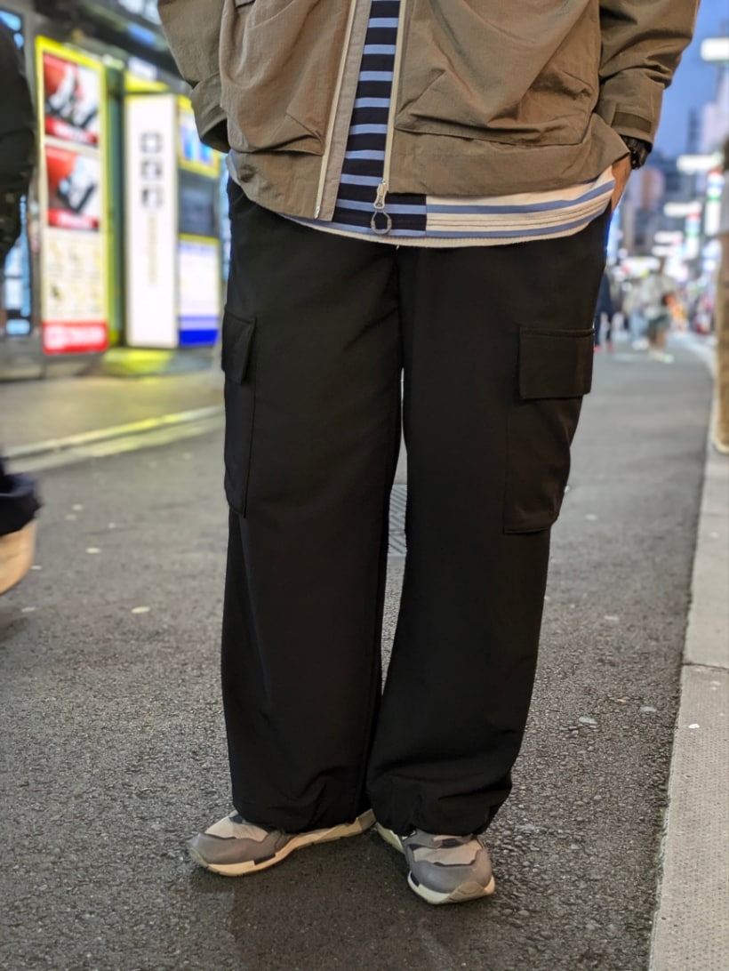 ブルー系のTシャツ/カットソー、ベージュ系のマウンテンパーカー、ブラック系のキャップを着用したメンズの秋コーディネートの2枚目の写真