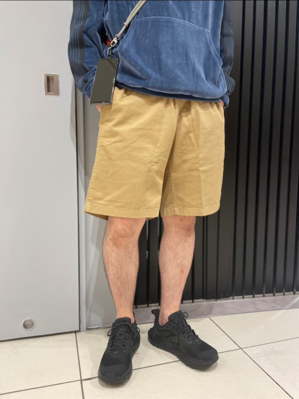 ベージュ系のその他パンツ、ブラック系のスニーカー、グリーン系のスマホグッズを着用したメンズの夏コーディネートの3枚目の写真