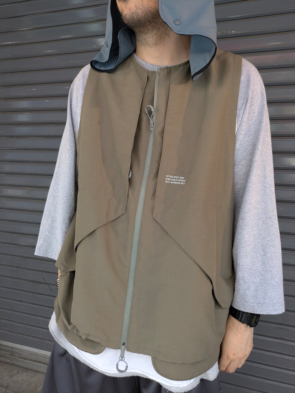 グレー系のベスト、ブラック系のサンダルを着用したメンズの夏コーディネートの2枚目の写真