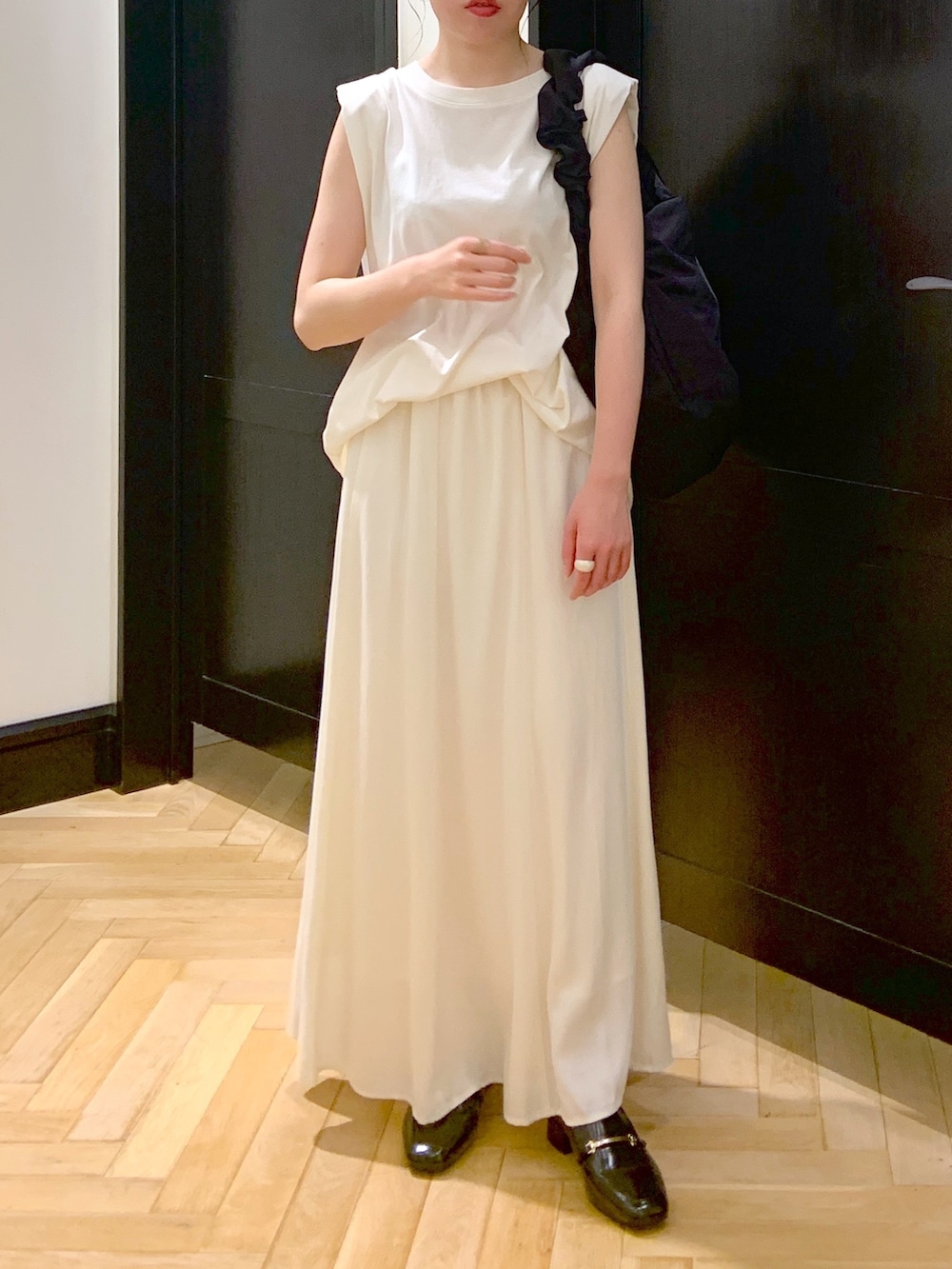 ブラック系のショルダーバッグ、ホワイト系のTシャツ/カットソー、ホワイト系のスカートを着用したレディースの夏コーディネートの2枚目の写真