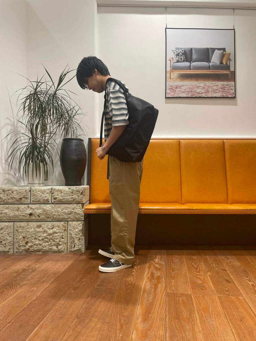 ベージュ系のチノパンツ、ブラック系のショルダーバッグ、グリーン系のTシャツ/カットソーを着用したメンズの夏コーディネートの2枚目の写真