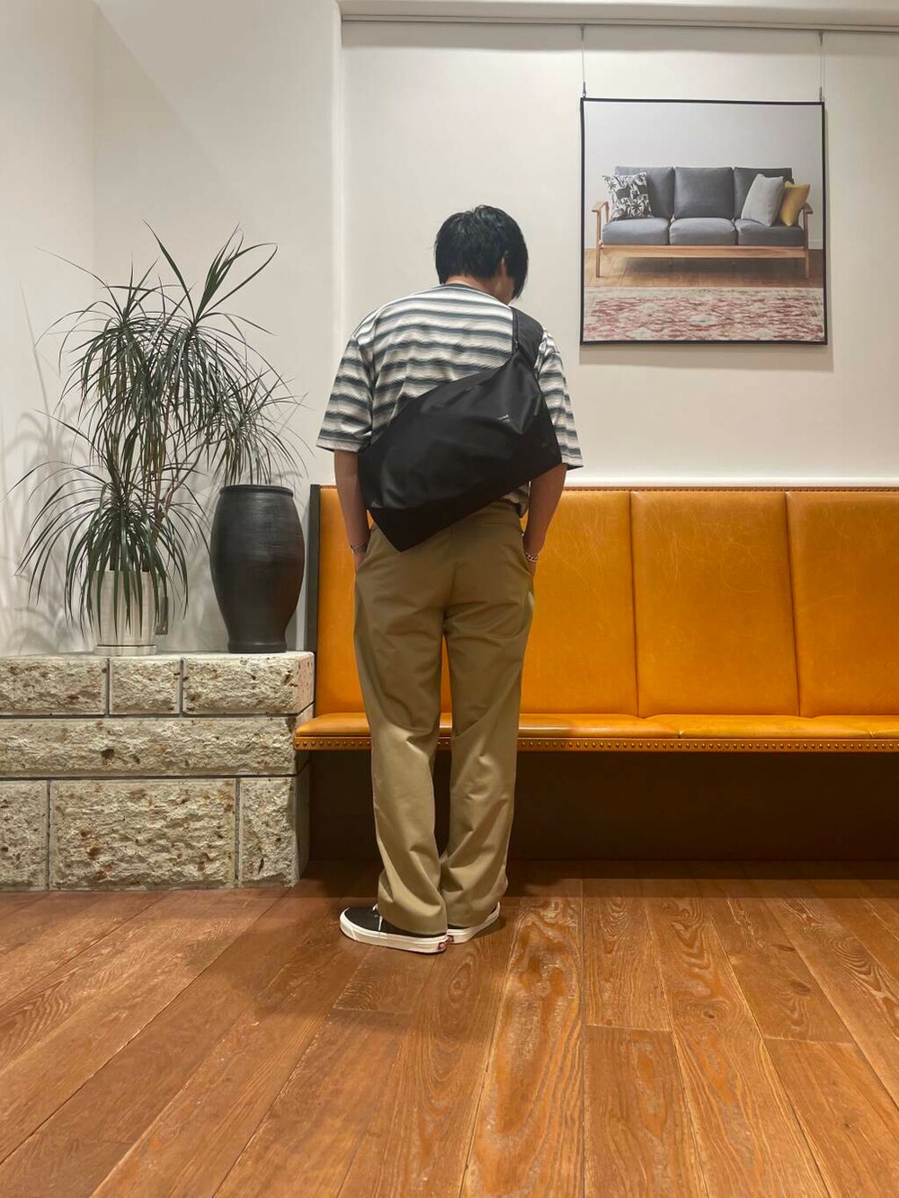 ベージュ系のチノパンツ、ブラック系のショルダーバッグ、グリーン系のTシャツ/カットソーを着用したメンズの夏コーディネートの3枚目の写真