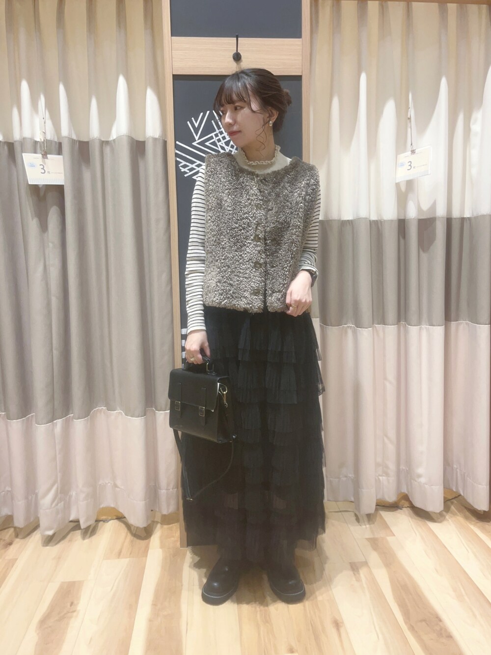 ブラック系のスカート、ホワイト系のニット/セーター、ブラック系のハンドバッグを着用したレディースの秋コーディネートの2枚目の写真