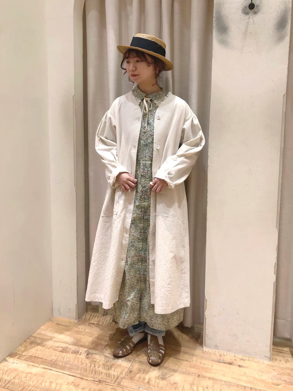 ホワイト系のノーカラーコート、グリーン系のワンピース、ベージュ系のサンダルを着用したレディースの春コーディネートの2枚目の写真