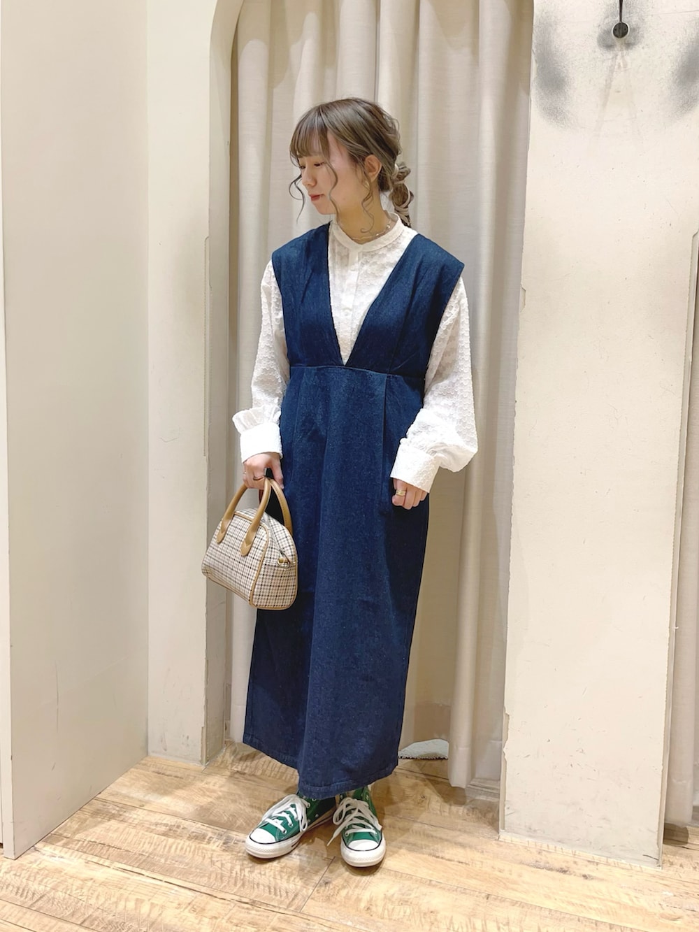 ベージュ系のショルダーバッグ、ホワイト系のシャツ/ブラウス、ブルー系のジャンパースカートを着用したレディースの冬コーディネートの2枚目の写真