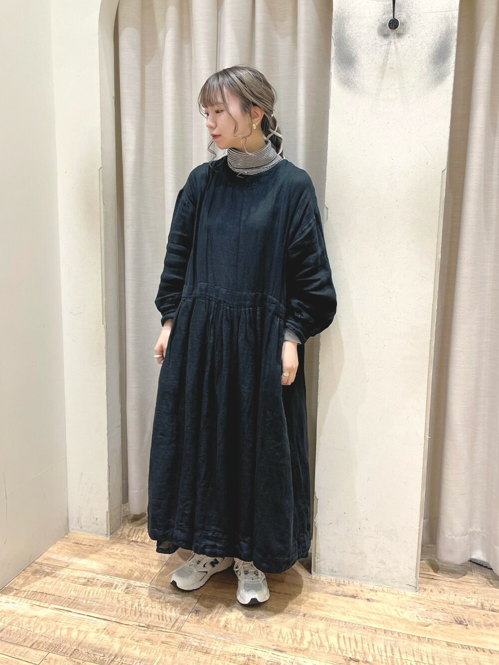 ブラック系のハンドバッグ、ブラック系のワンピース、ホワイト系のスニーカーを着用したレディースの秋コーディネートの2枚目の写真