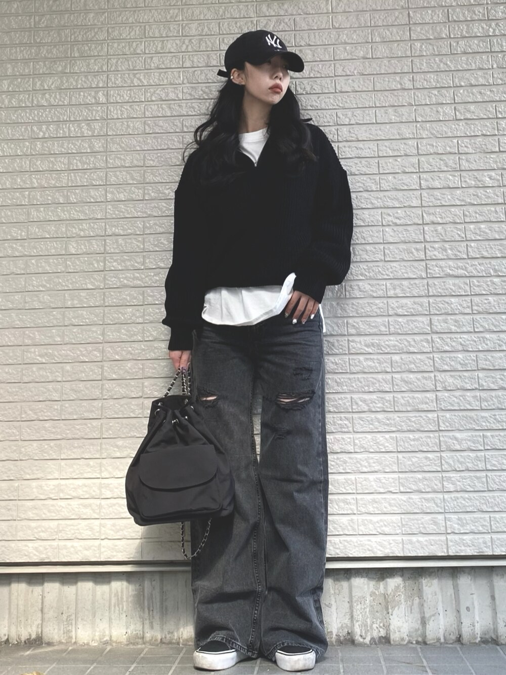 ブラック系のニット/セーター、ブラック系のバックパック/リュック、グレー系のデニムパンツを着用したレディースの冬コーディネートの2枚目の写真