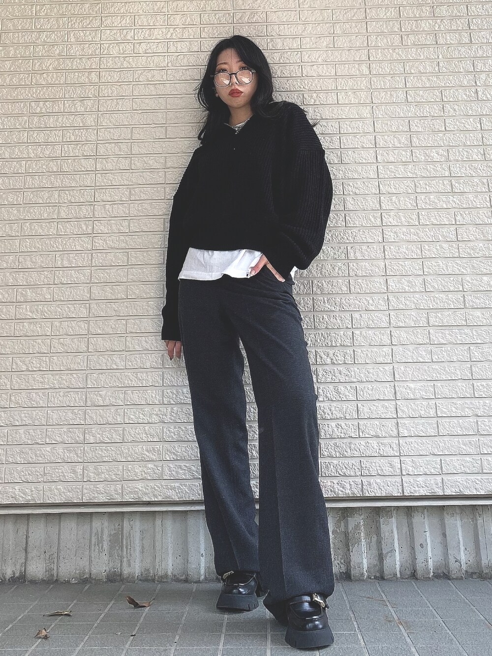 ブラック系のニット/セーター、グレー系のパンツ、ブラック系のローファーを着用したレディースの春コーディネートの2枚目の写真