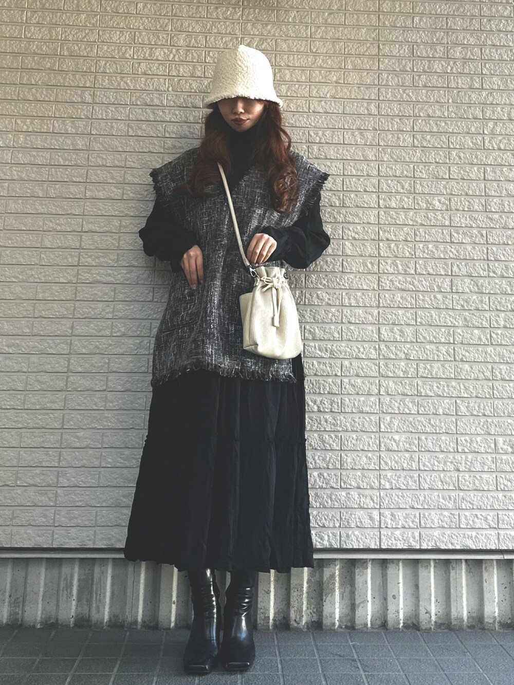 ブラック系のベスト、ブラック系のワンピース、ブラック系のブーツを着用したレディースの冬コーディネートの2枚目の写真