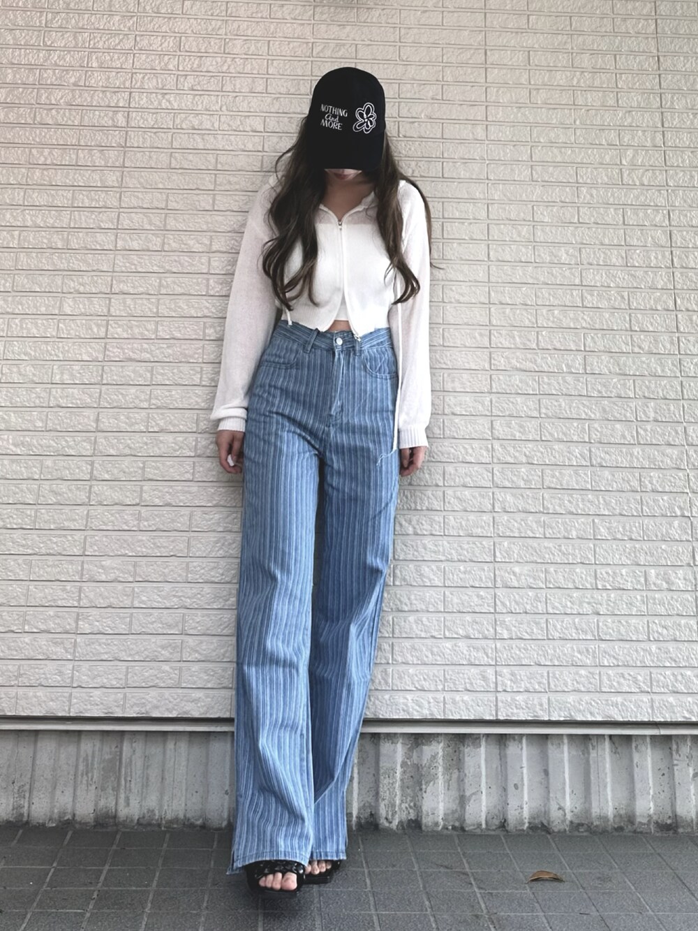 ホワイト系のパーカー、ブルー系のデニムパンツ、ブラック系のサンダルを着用したレディースの春コーディネートの2枚目の写真