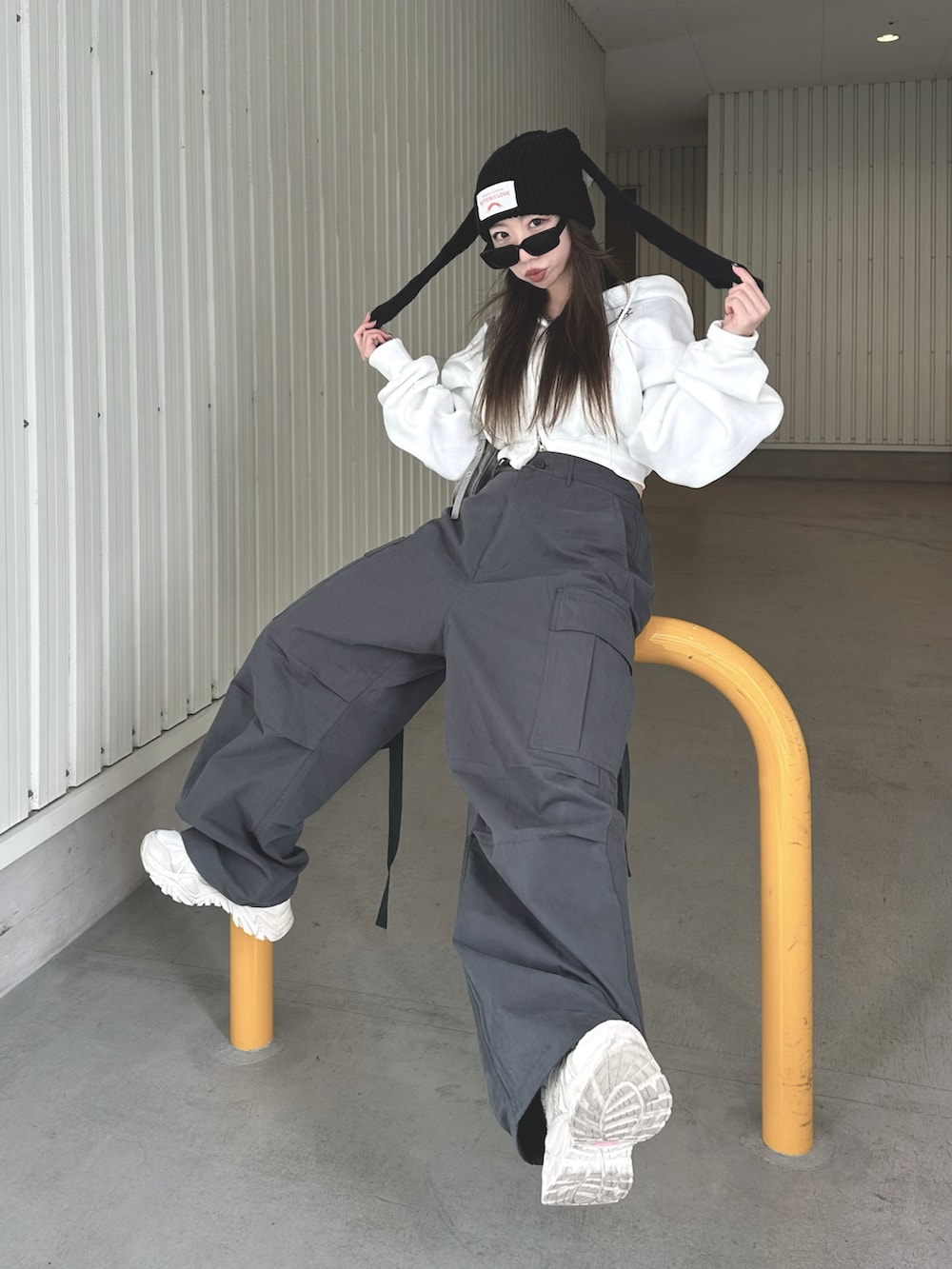 グレー系のカーゴパンツ、グレー系のバッグ、ホワイト系のパーカーを着用したレディースの冬コーディネートの2枚目の写真