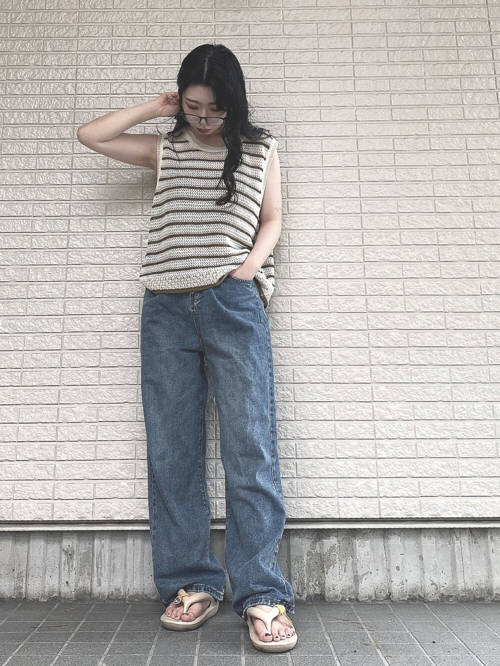 ベージュ系のベスト、ブルー系のデニムパンツ、ベージュ系のサンダルを着用したレディースの夏コーディネートの2枚目の写真