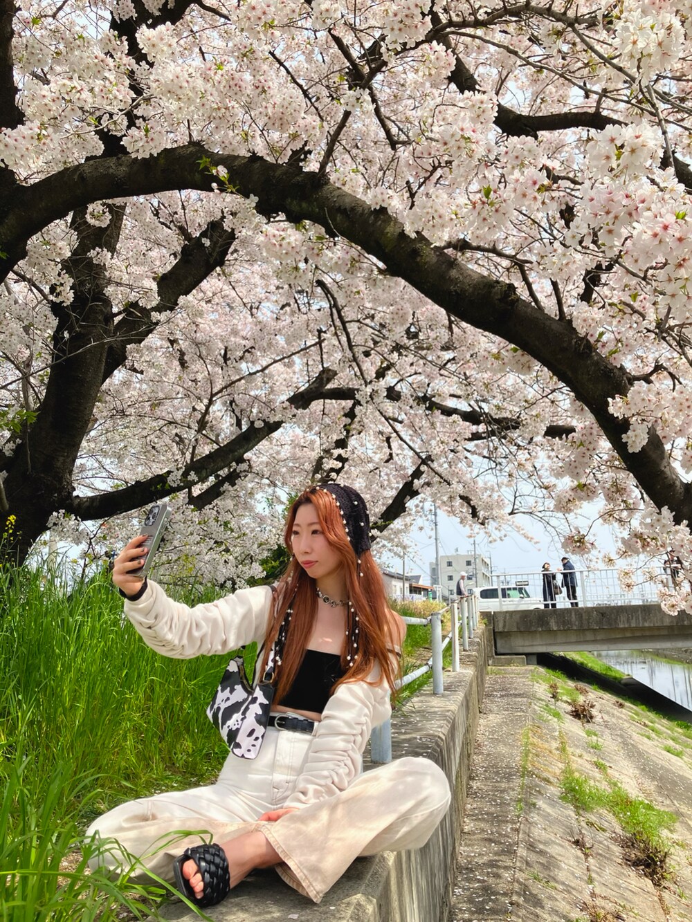 ホワイト系のトップス、ホワイト系のデニムパンツ、ブラック系のサンダルを着用したレディースの春コーディネートの3枚目の写真