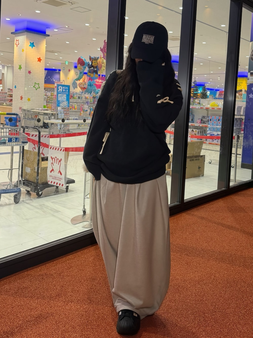 ブラック系のスニーカー、ブラック系のニット/セーター、グレー系のスウェットパンツを着用したレディースの冬コーディネートの2枚目の写真