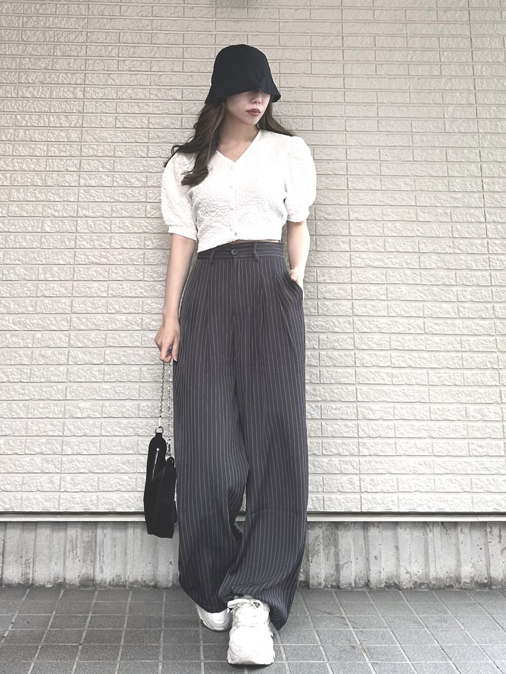 ホワイト系のシャツ/ブラウス、グレー系のスラックス、ホワイト系のスニーカーを着用したレディースの夏コーディネートの2枚目の写真