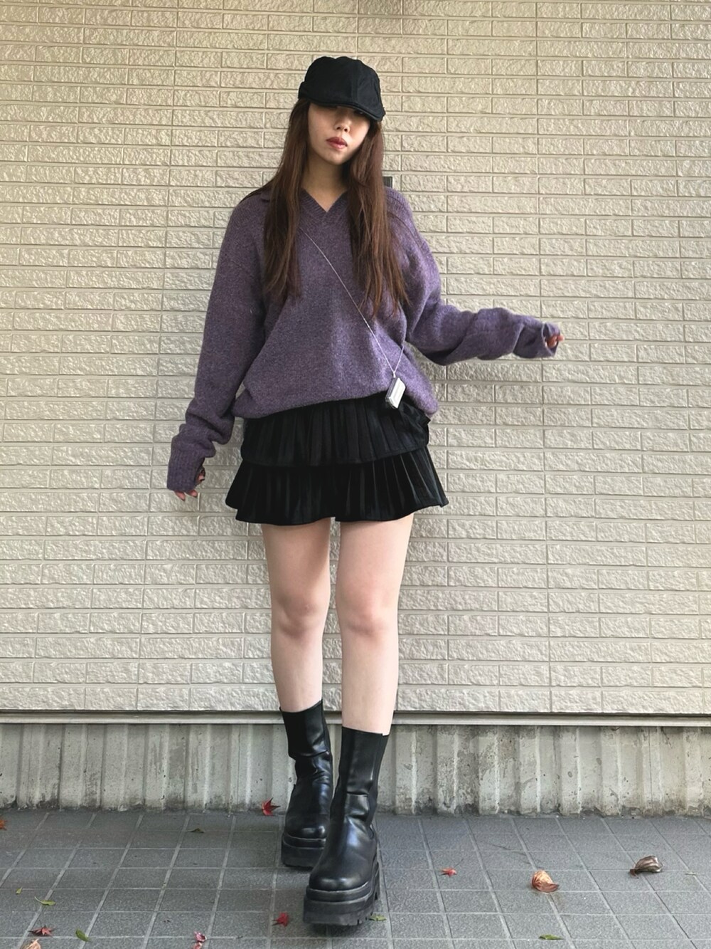 パープル系のニット/セーター、ブラック系のスカート、ブラック系のブーツを着用したレディースの冬コーディネートの2枚目の写真