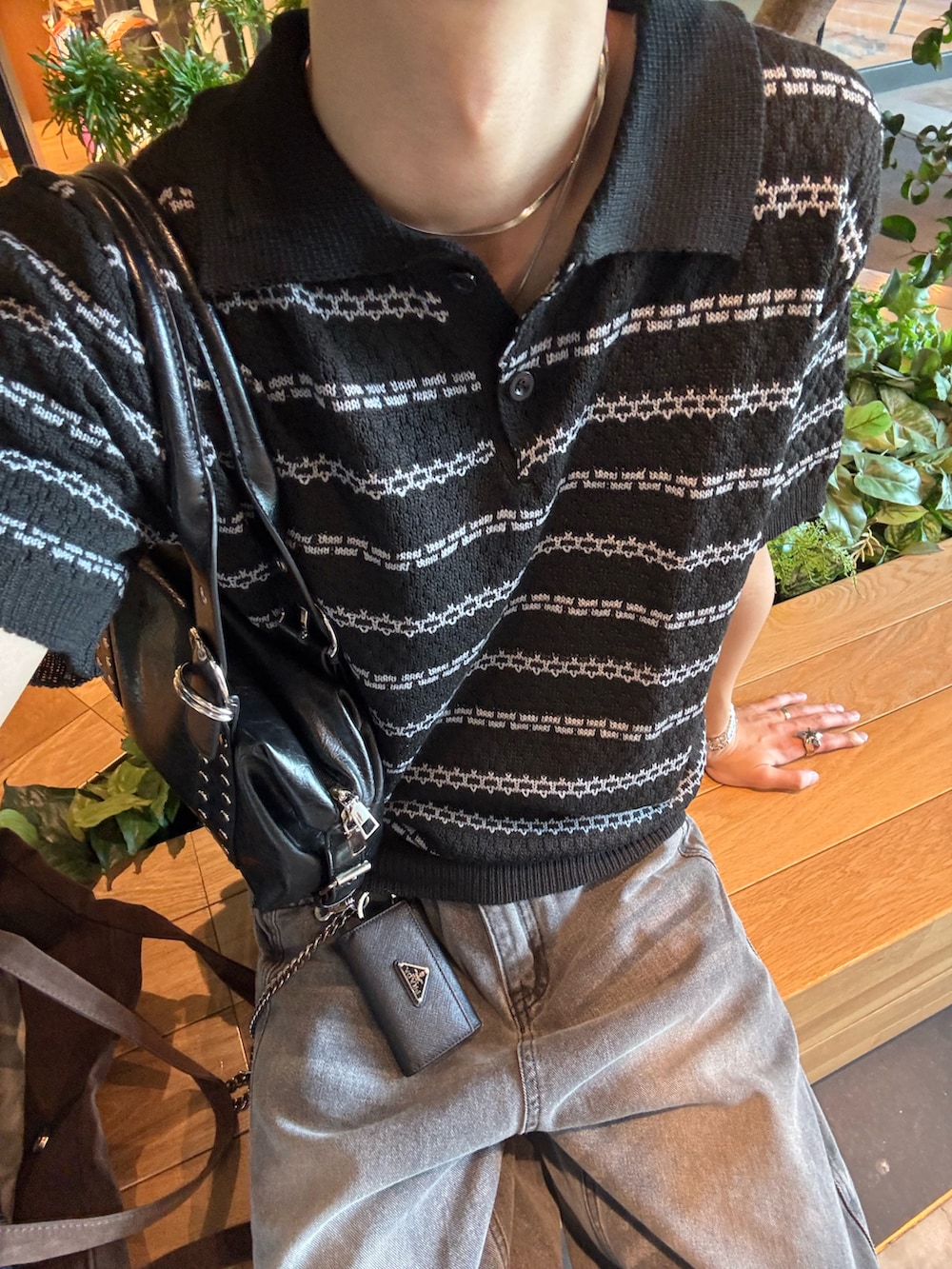 ブラック系のポロシャツ、グレー系のデニムパンツ、ブラック系のサンダルを着用したメンズの春コーディネートの4枚目の写真